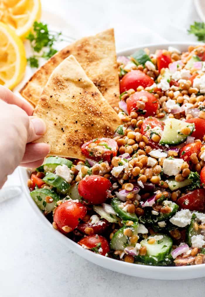 Scooping the lentil salad with a pita chip.