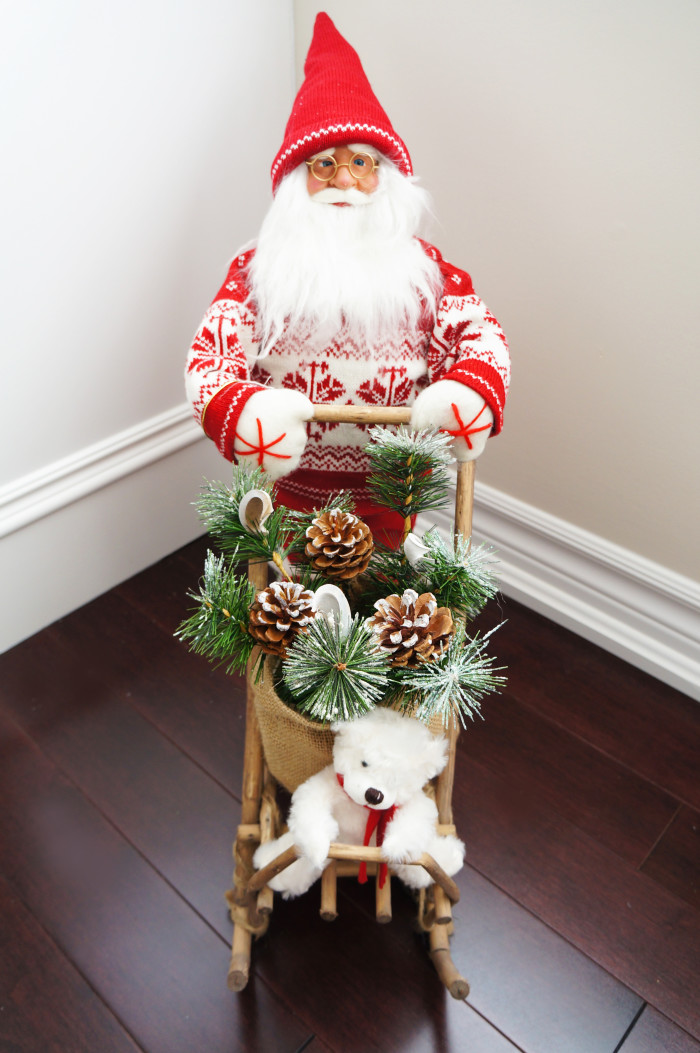 Santa doll pushing a sled with pine branches, pine cones, and a stuffed polar bear