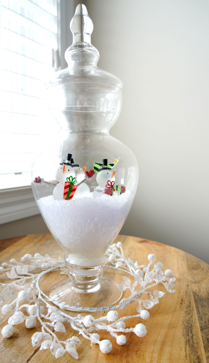 Clear container filled with fake snow and mini snowmen