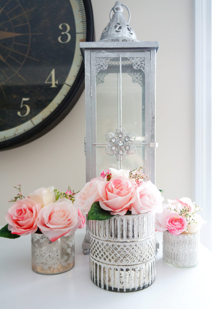 Pink Spring rose bouquets in silver votives with candles on fireplace mantel 
