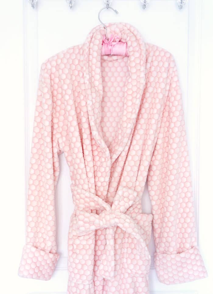 Pink and white textured bath robe hanging from a hanger