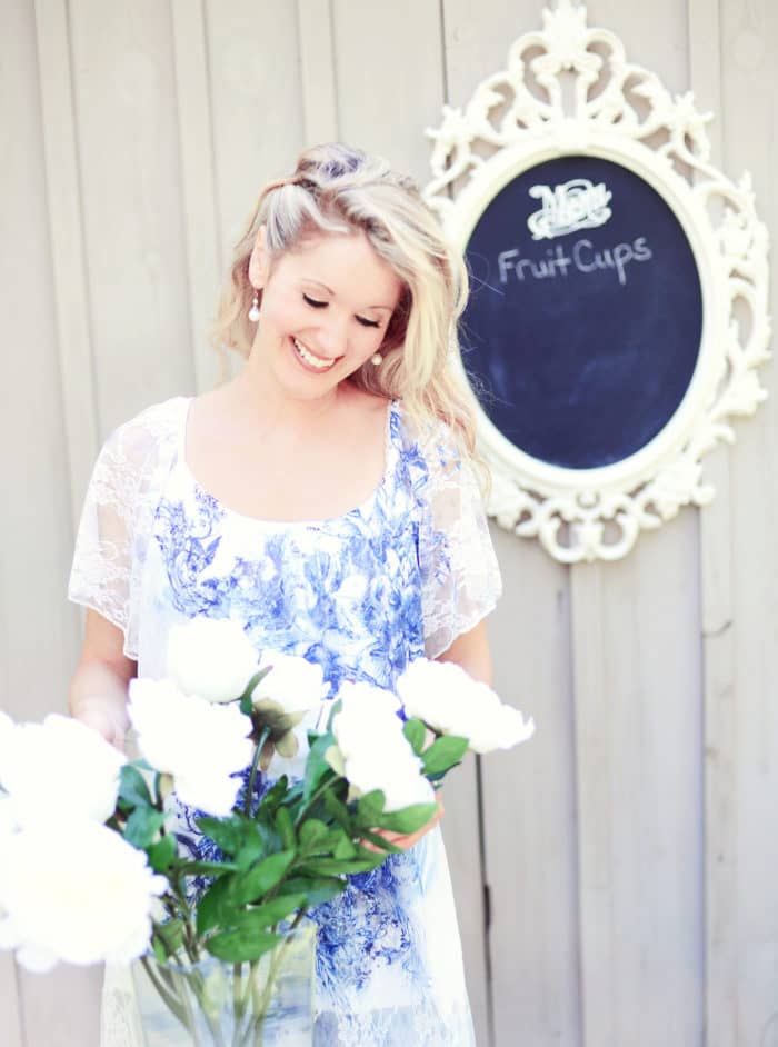 Elysia in a blue and white dress arranging white flowers