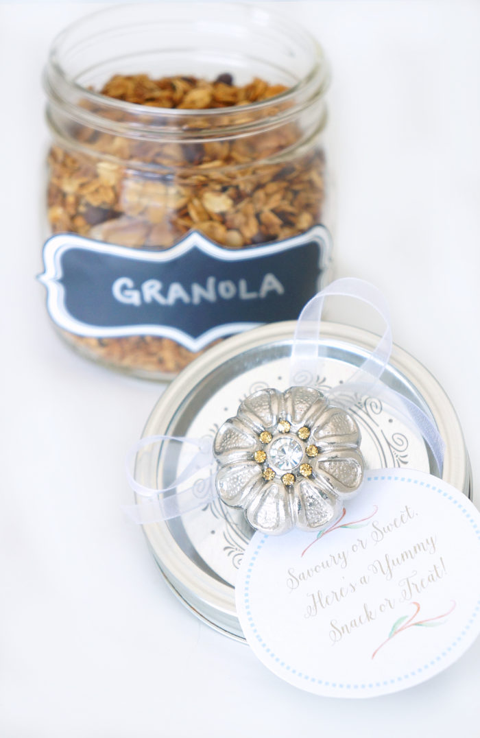 Mason jar top with a decorative knob attached and a tag that says \"Savory or Sweet Here\'s a Yummy Snack or Treat!\" in front of an open jar of granola