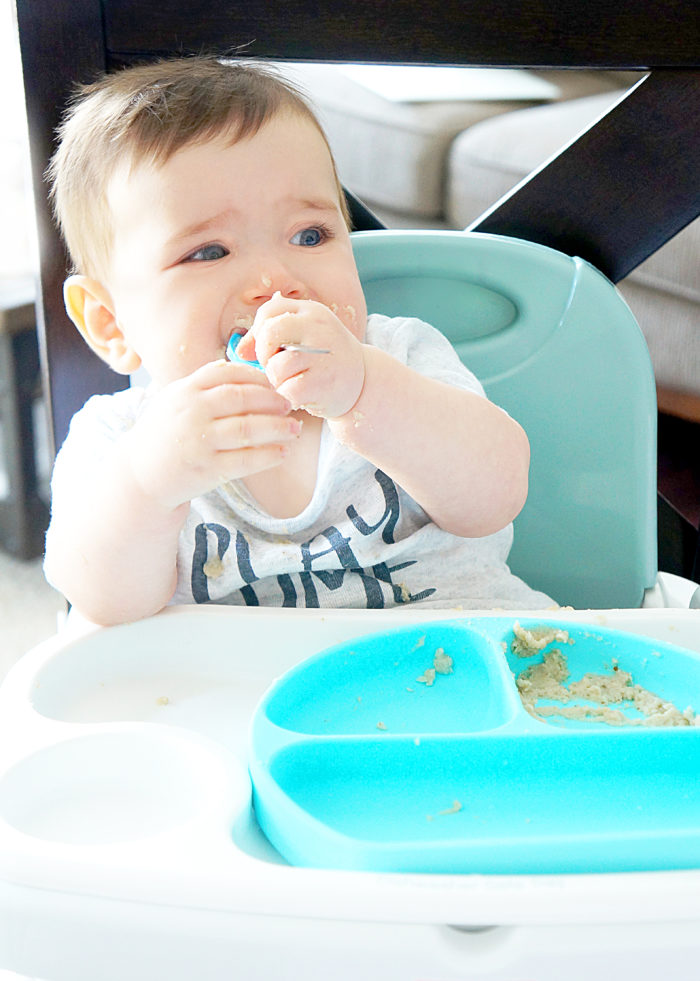 Baby eating off of blue plate in a high chair