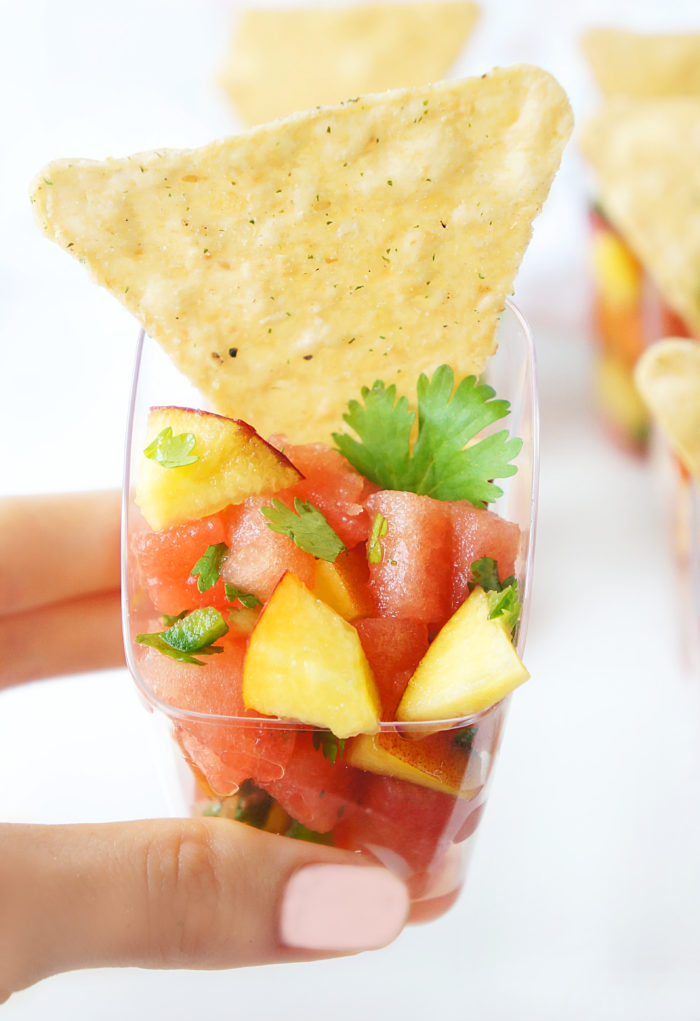 Small cup of Watermelon Peach Salsa with a tortilla chip sticking out