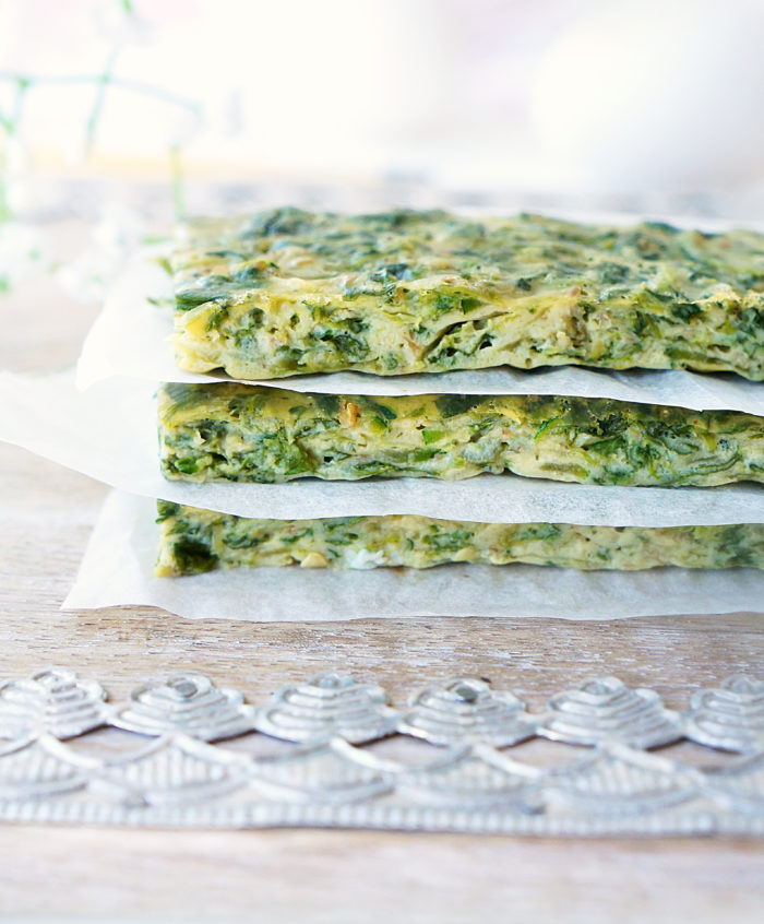 Stack of three spinach zucchini frittata fingers separated by parchment paper