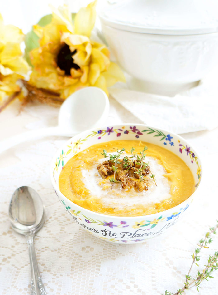 Bowl of Roasted Sweet Potato Soup with Maple Glazed Walnuts next to a spoon