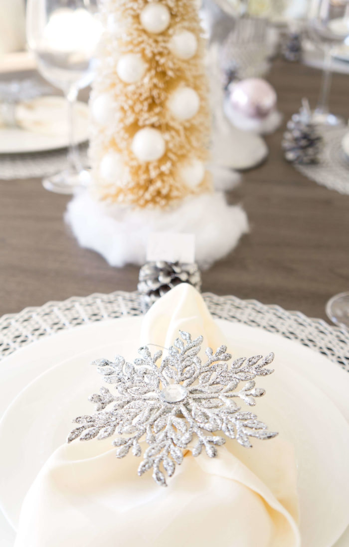 Silver snowflake napkin ring around an ivory napkin on a white dish