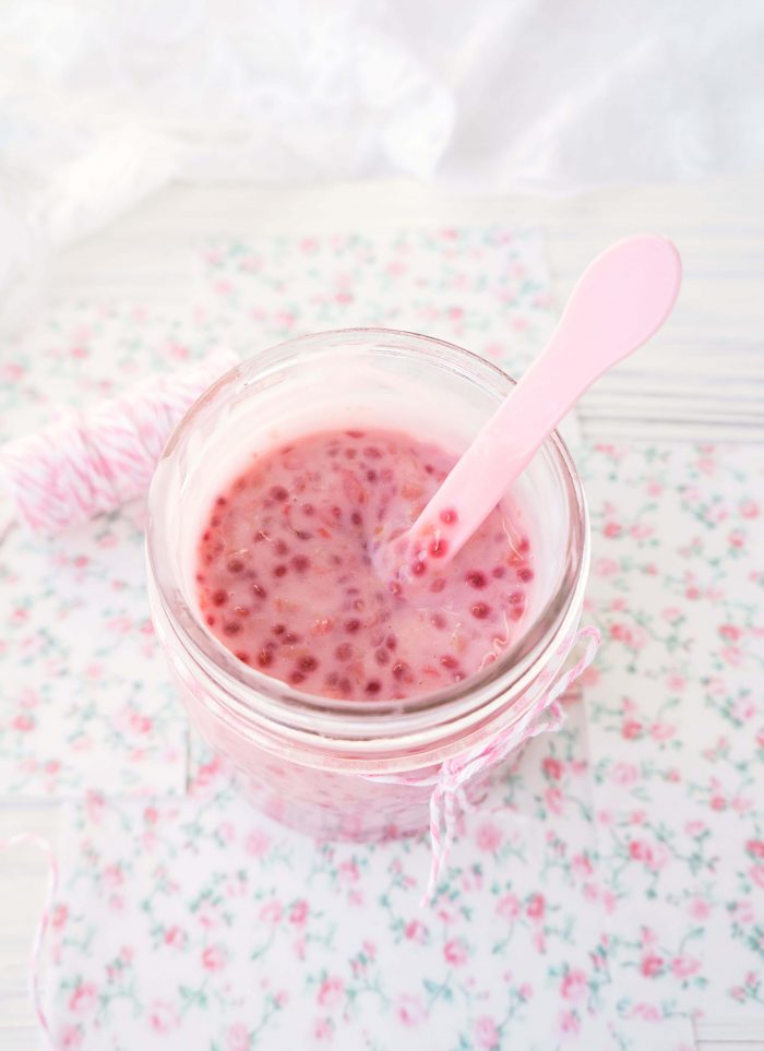 Mason jar of raspberry yogurt stirred with a pink spoon