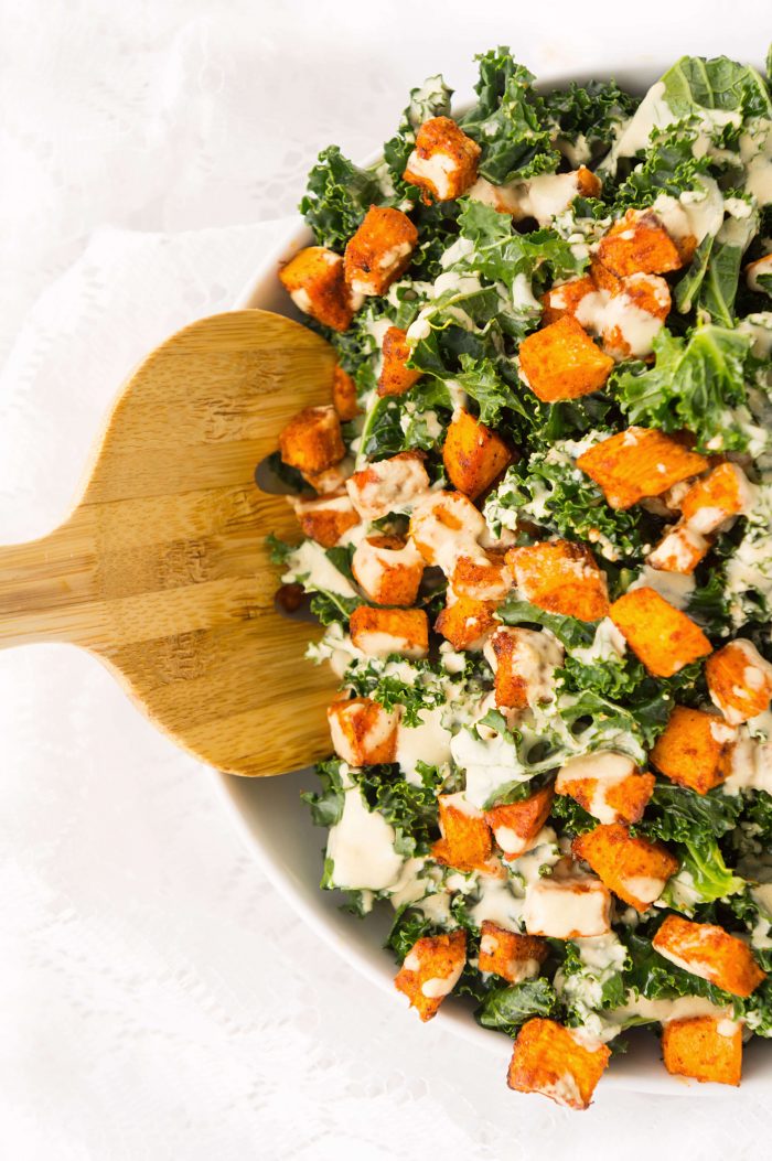 Spoon scooping Sweet Potato Kale Bowl with Creamy Roasted Garlic Dressing 