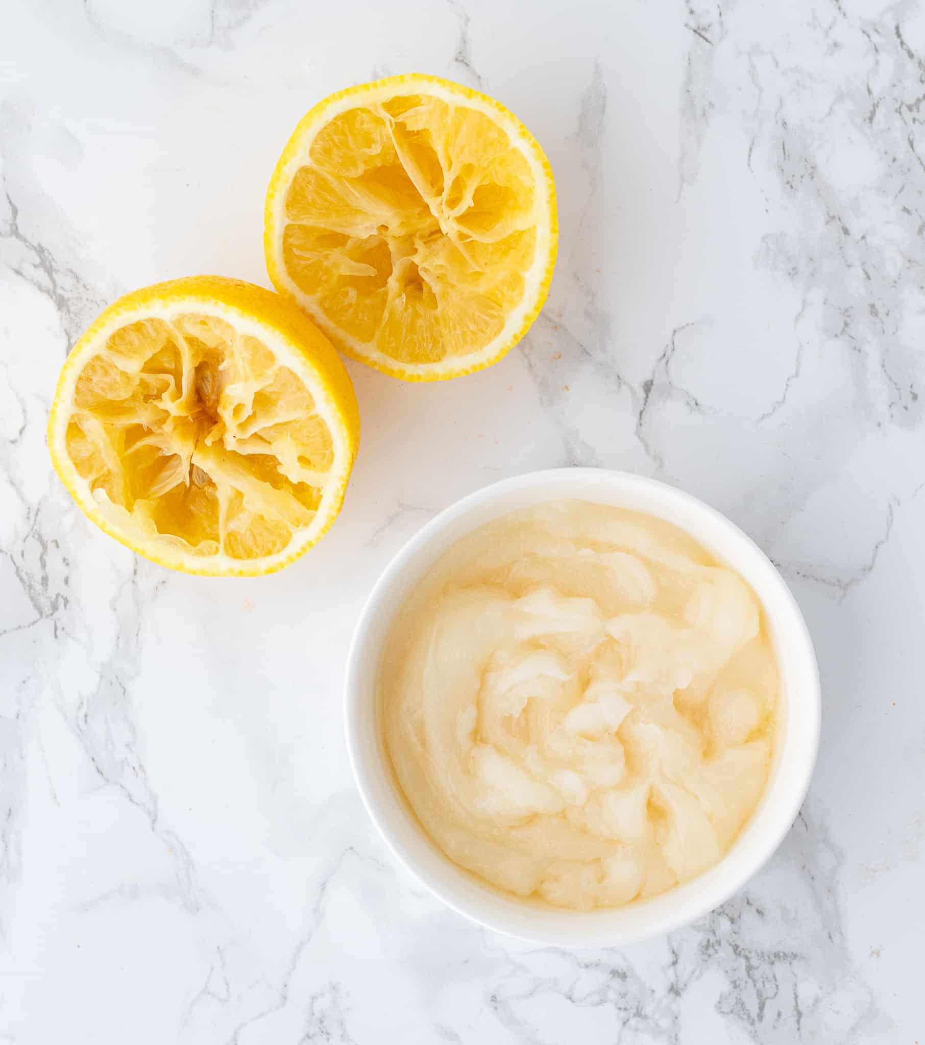 Lemon glaze in a bowl with freshly squeezed lemon