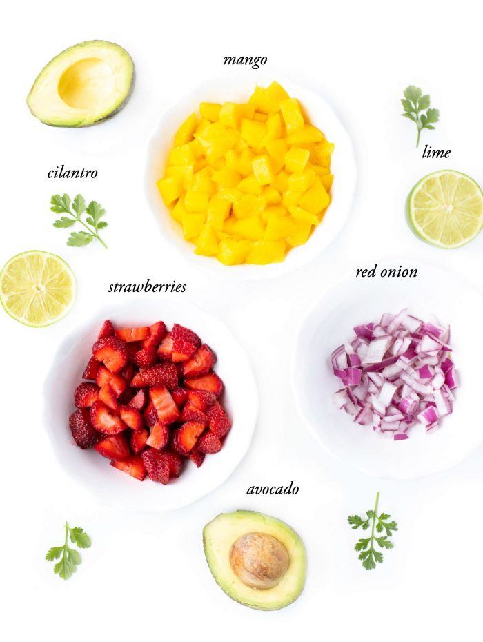 Ingredients for Strawberry Mango Avocado Salsa including strawberries, lime, red onion, avocado, and mango