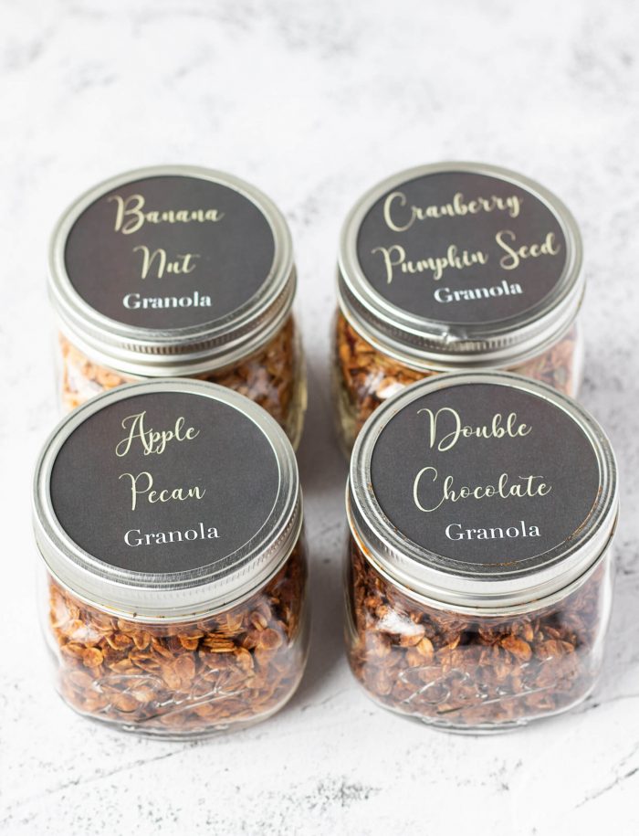 Jars labeled with four different types of granola: Banana nut, Cranberry pumpkin seed, apple pecan, and double chocolate