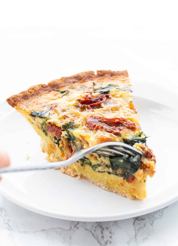 eating a slice of spinach bacon quiche 