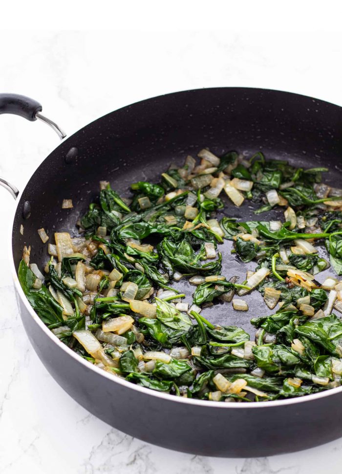 spinach and mushrooms cooking in a skillet