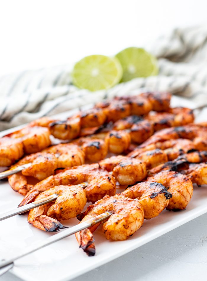 Grilled shrimp skewers on a platter with lime.