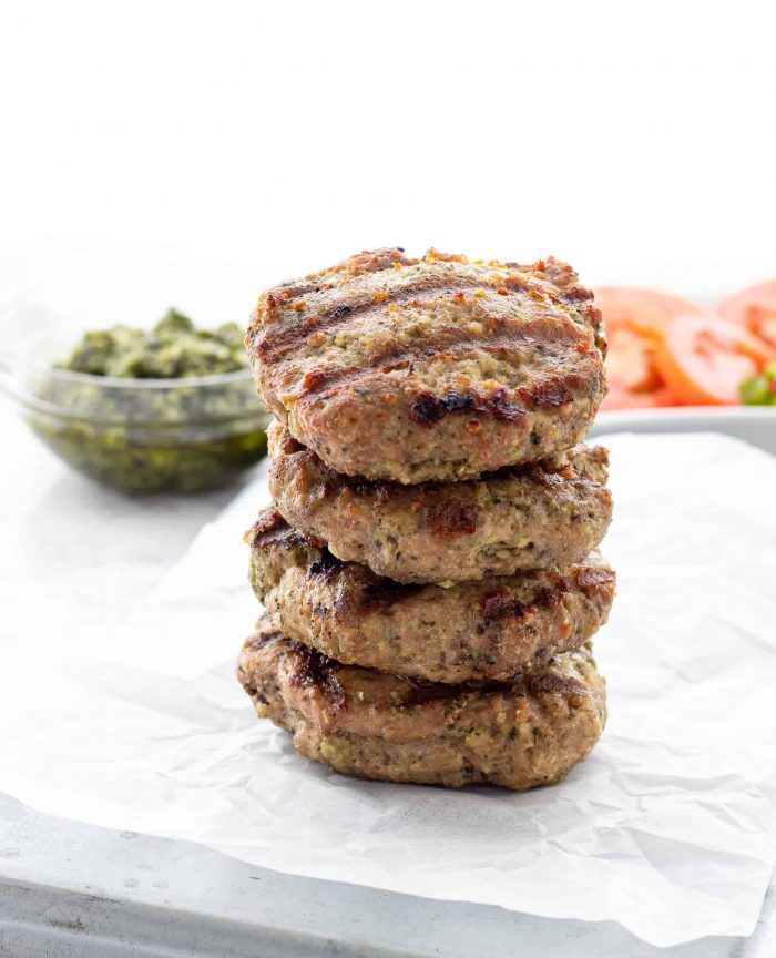 Four chicken pesto burgers stacked on top of each other.