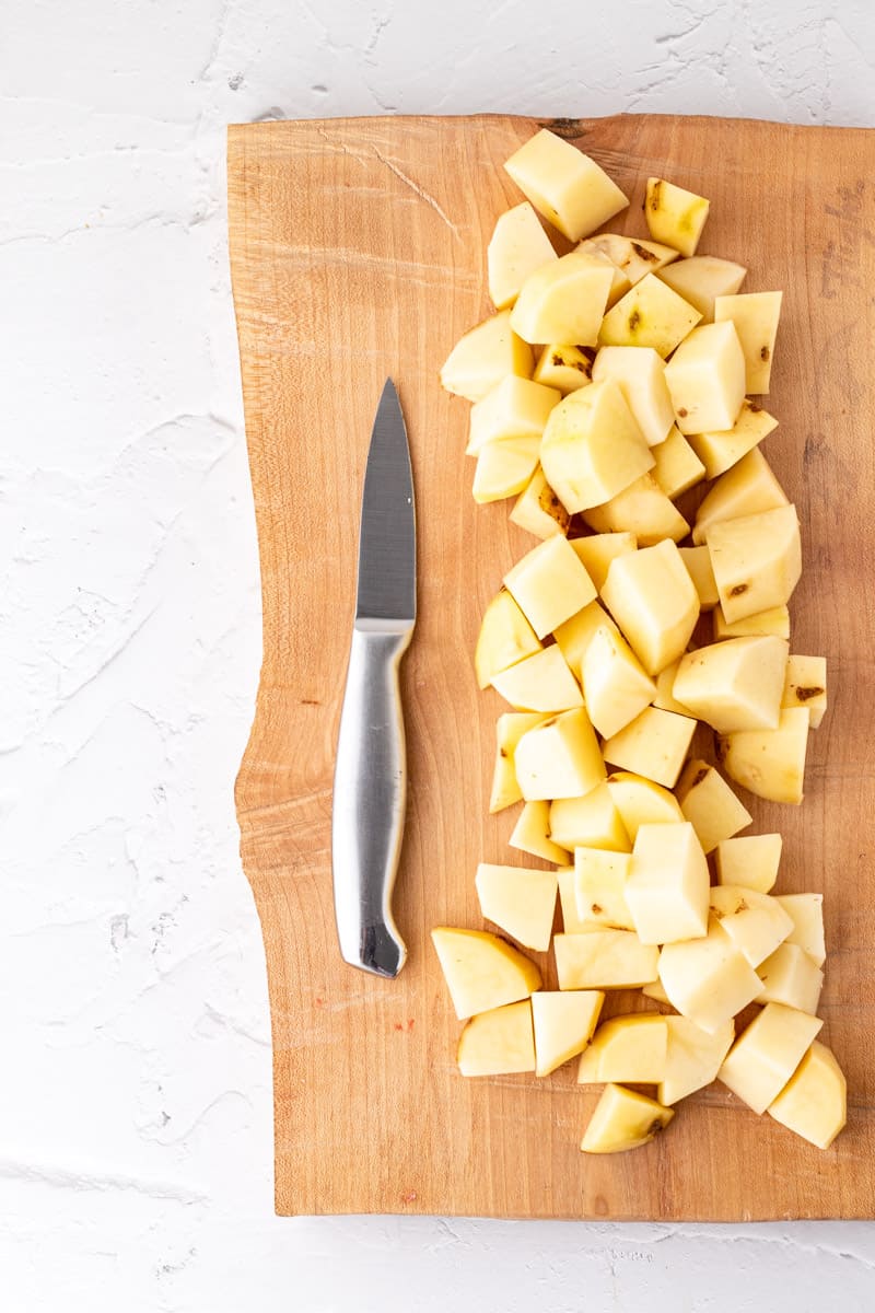 Cut potatoes on a wooden chopping board.