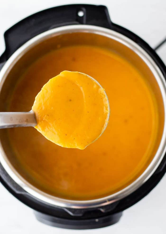A ladle of the soup being held above the Instant Pot.