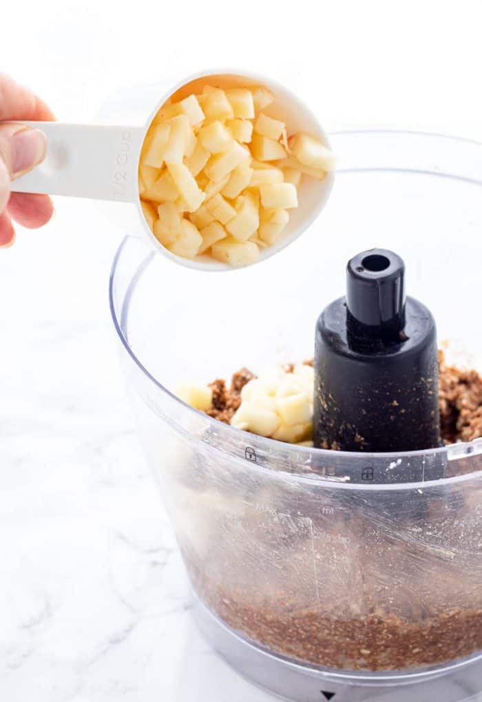 Adding apple chunks to energy ball mixture in food processor