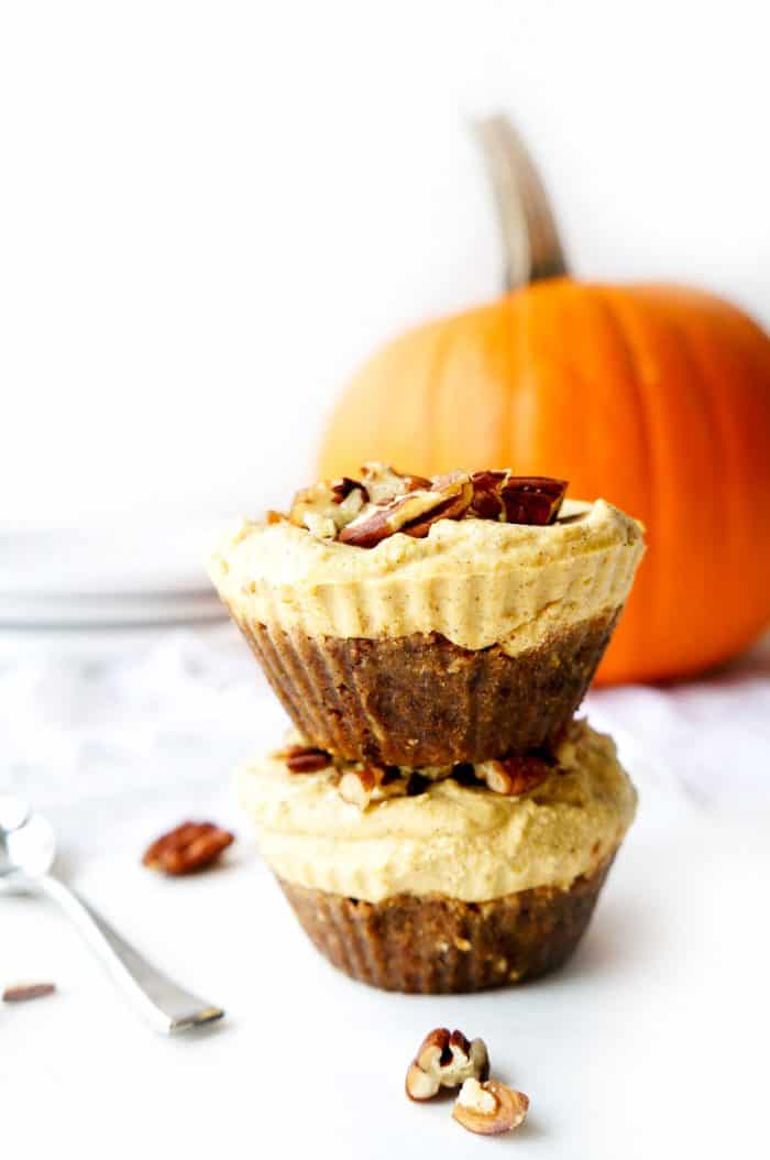 two vegan cheesecake bites stacked with pumpkin in background