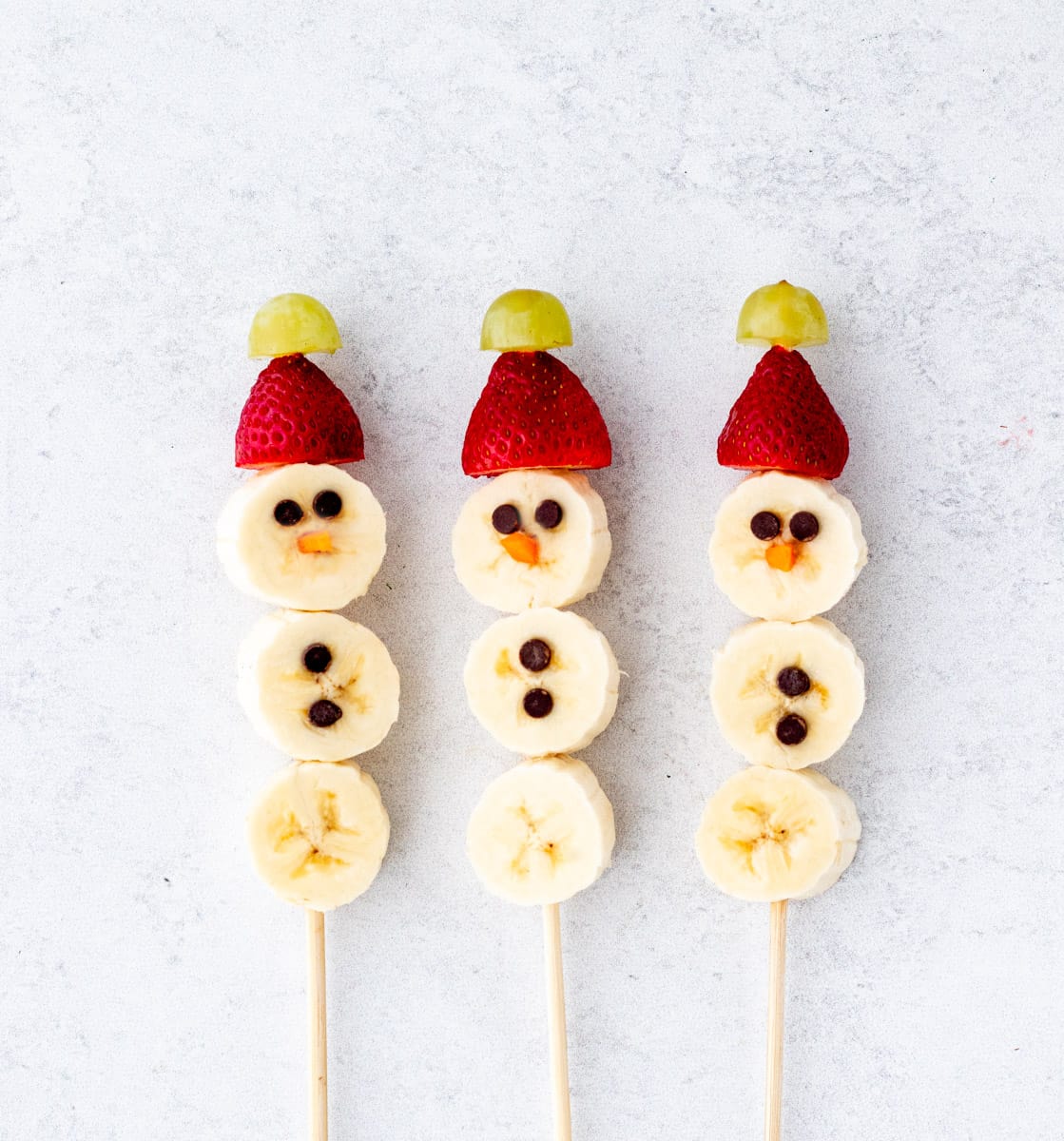 Banana slices, strawberries, grapes and mini dark chocolate chips on skewers to make banana snowmen.