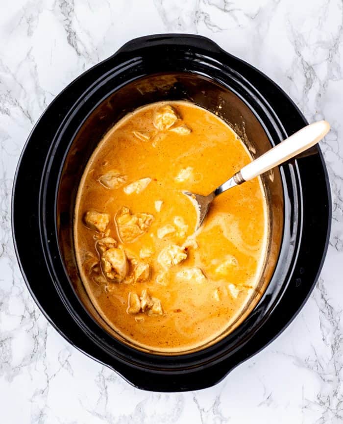serving spoon in slow cooker with peanut sauce and chicken