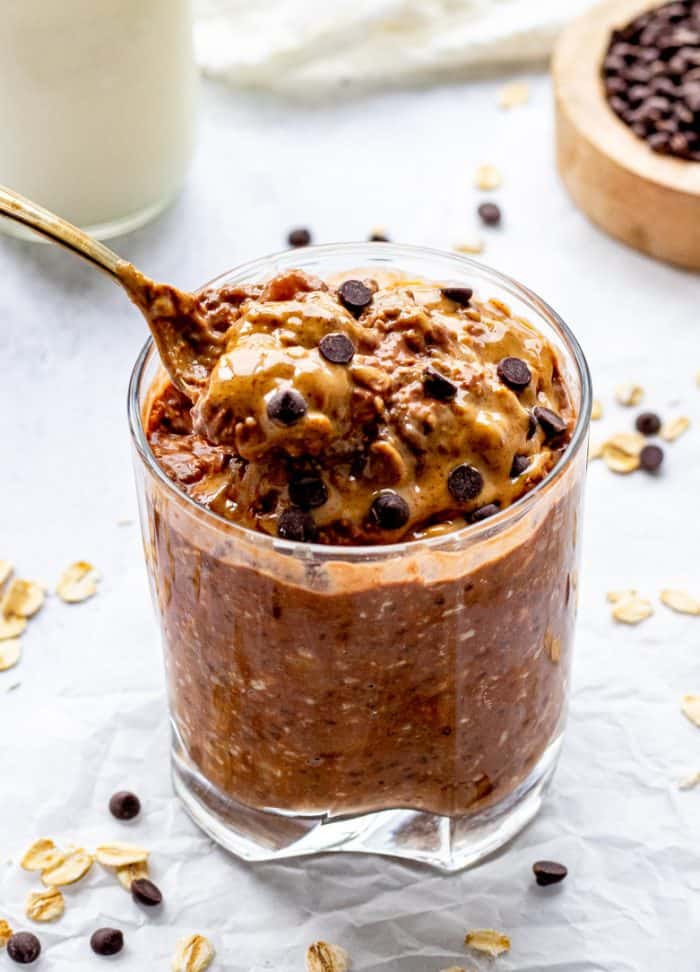 spoon scooping up chocolate overnight oats out of glass