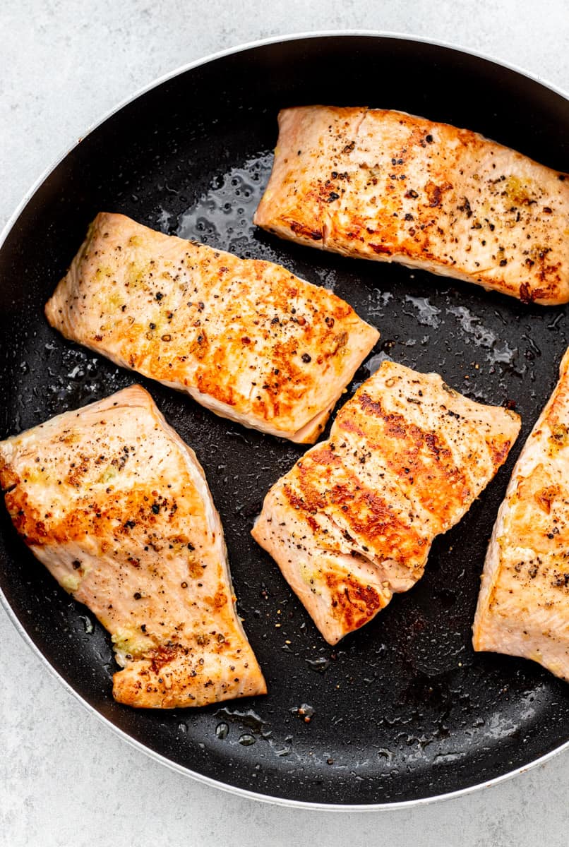 Cooked salmon fillets in a skillet.