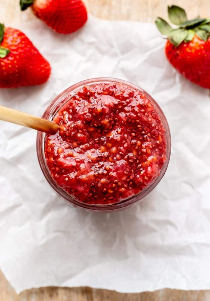 Strawberry jam in a jar with a wooden spoon.