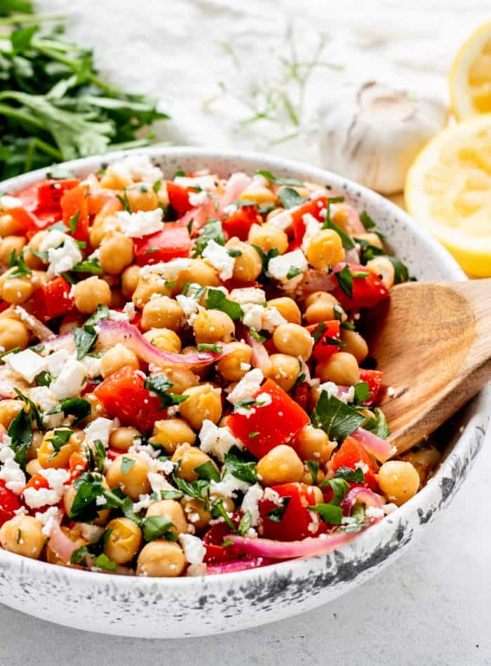 Healthy chickpea salad with feta in a large white serving bowl.