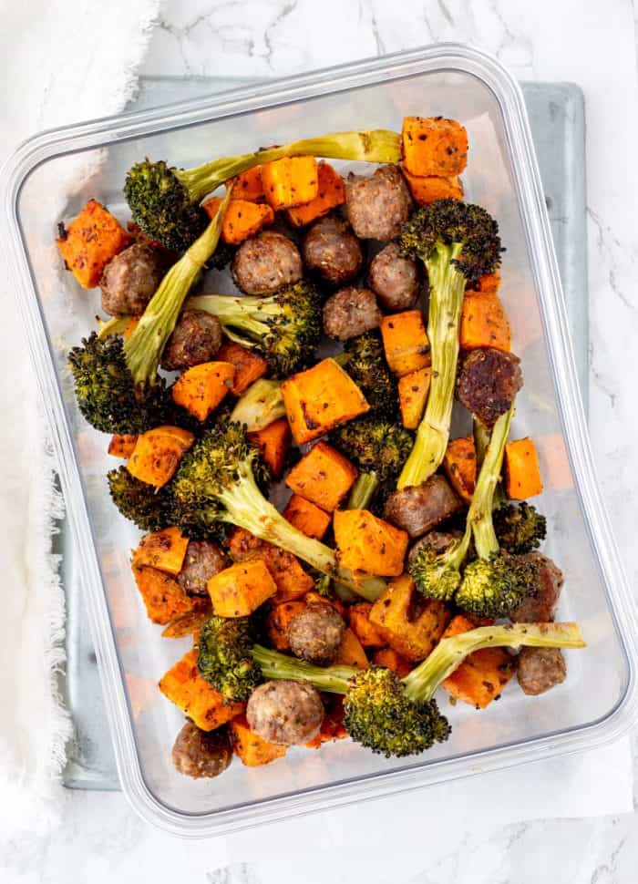 Sheet pan sausage and veggies in a glass container.