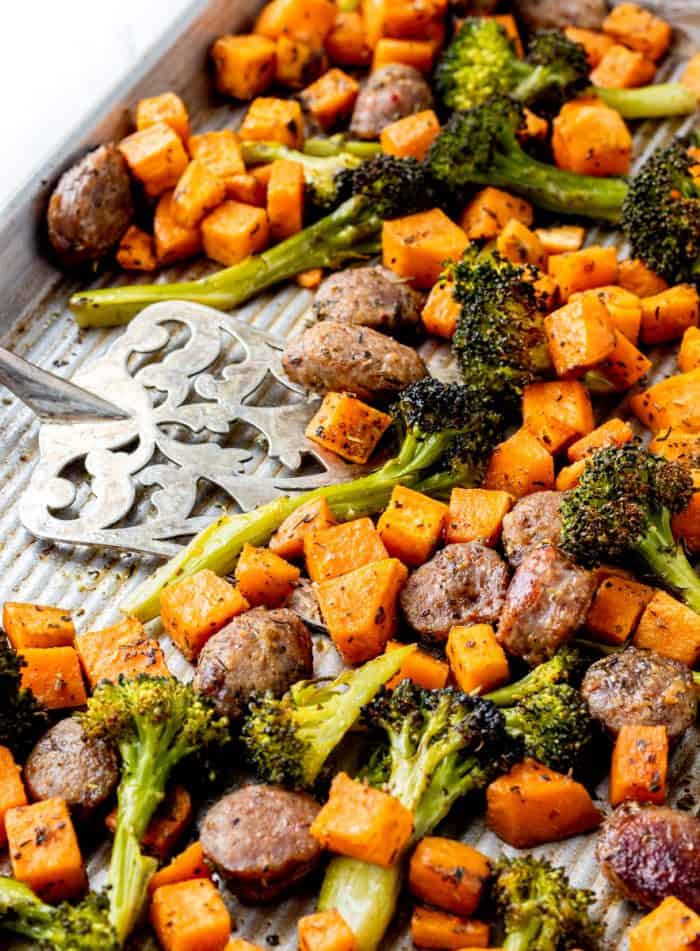 A spatula on a sheet pan with the cooked sausage and veggies.