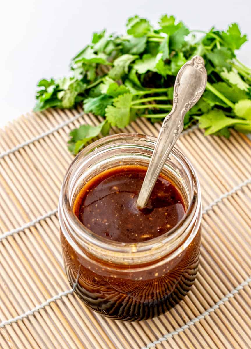 The Asian dressing in a glass jar with a spoon.