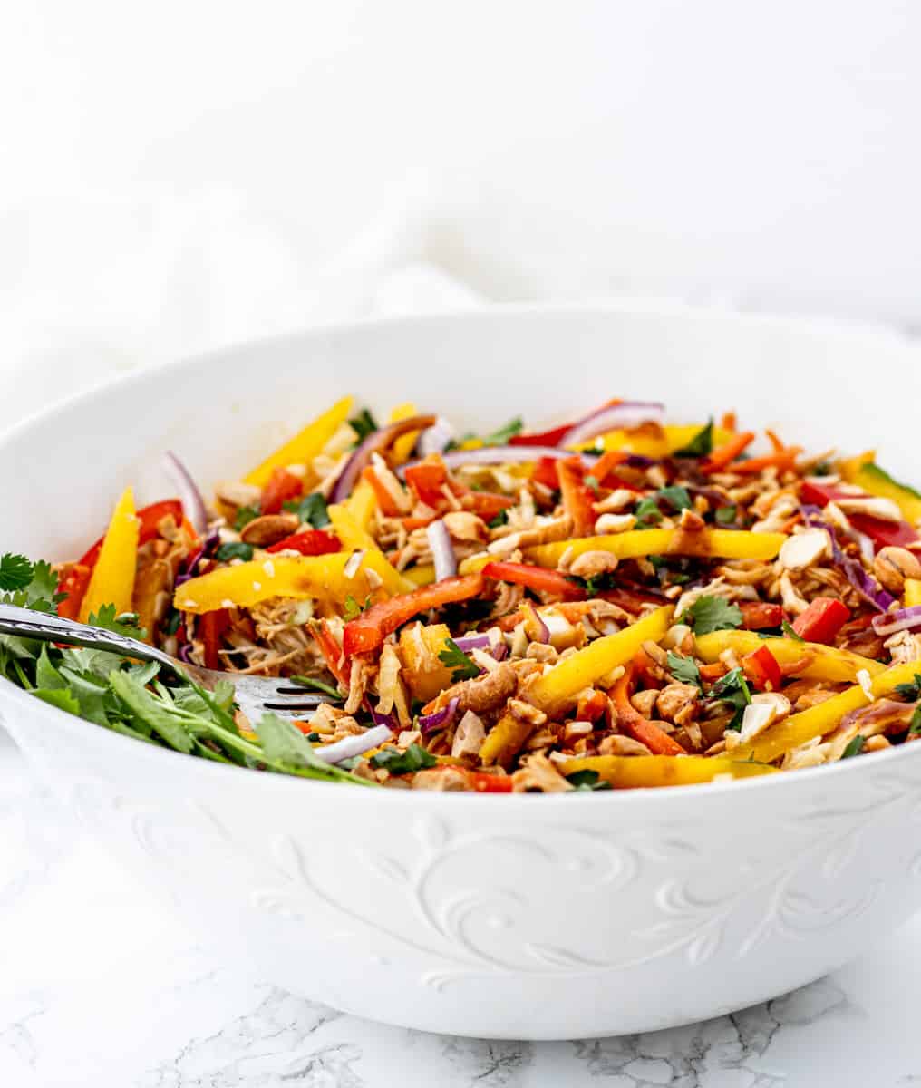 Side view of the Thai mango salad in a white bowl.