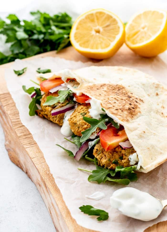 falafels in a pita with vegetables and tzatziki on a wooden cutting board