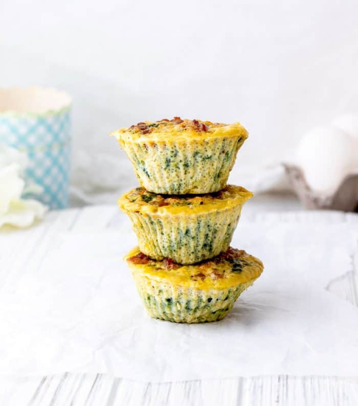 three egg muffins stacked on top of each other with blue cups and eggs in background