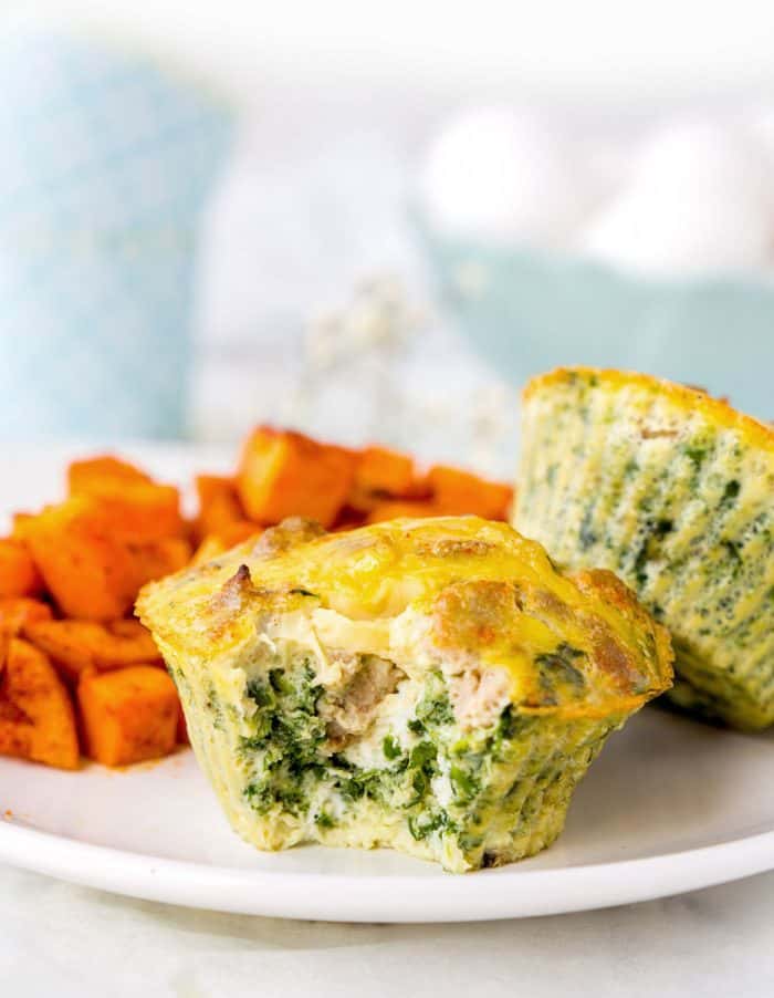 Two spinach egg muffins on white plate with baked sweet potatoes