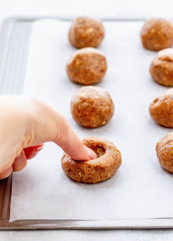Making a dent in each cookie ball with a thumb.