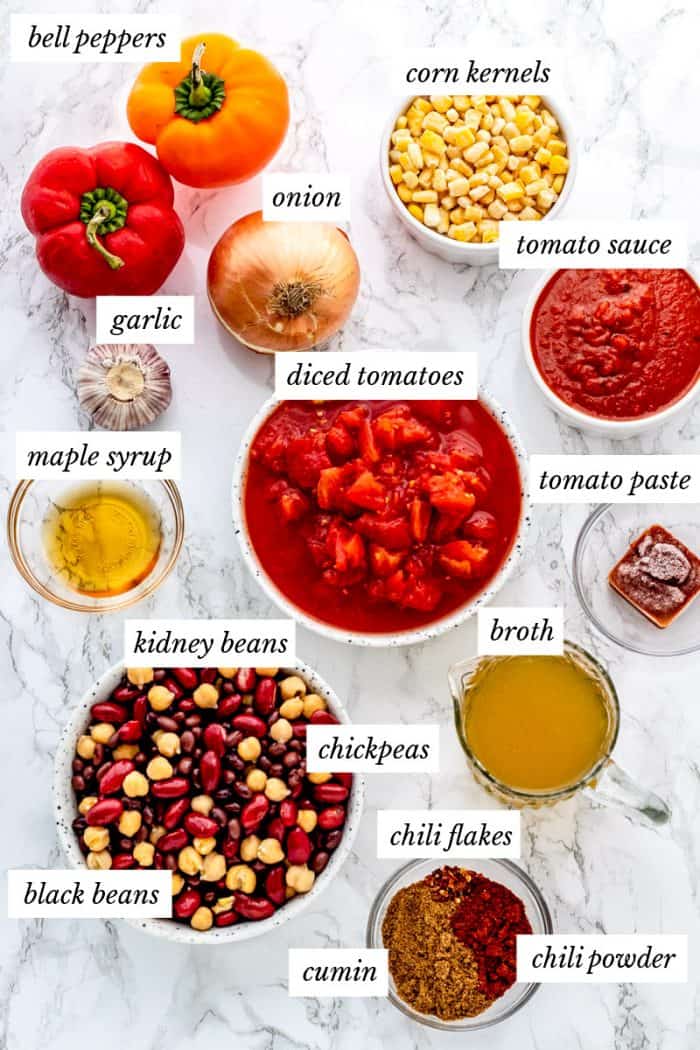 Ingredients for vegan chili recipe on a marble background with labels