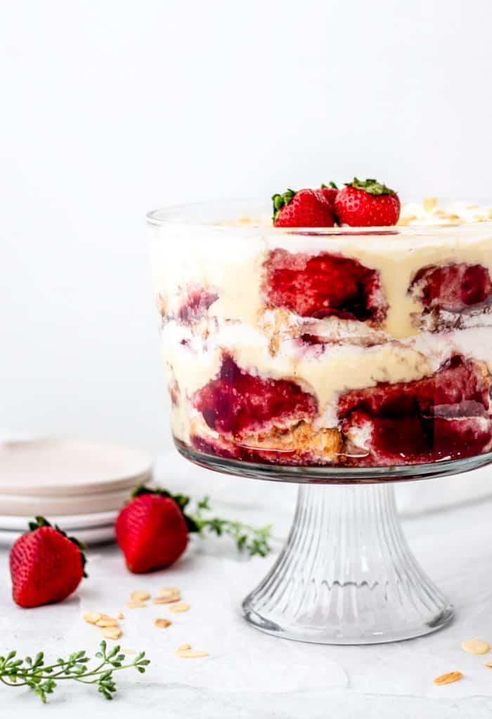 close up of the English trifle in a large clear glass serving bowl topped with strawberries