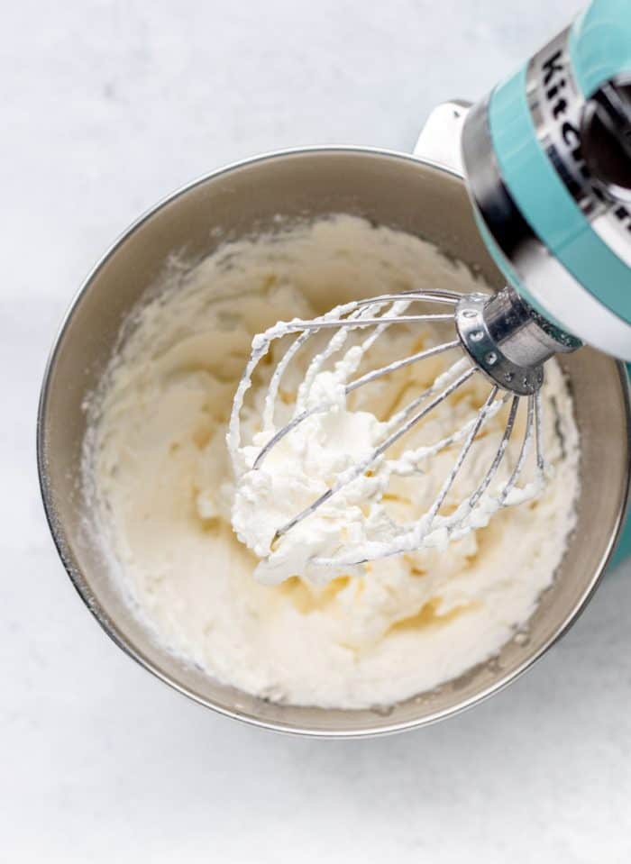 whipped cream on the whisk of an electric mixer over a bowl
