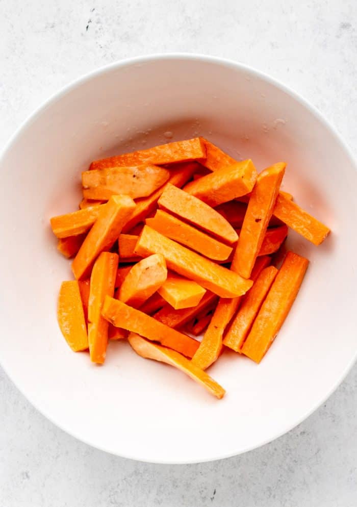 a large bowl filled with sweet potato cut into fries.