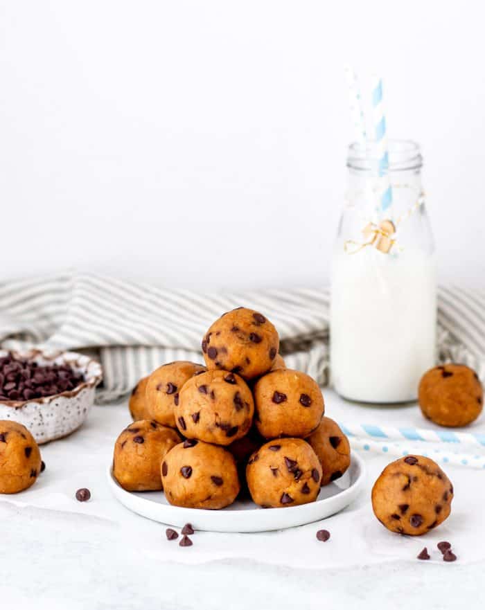 Vegan cookie dough balls on a plate next to a bottle of milk.