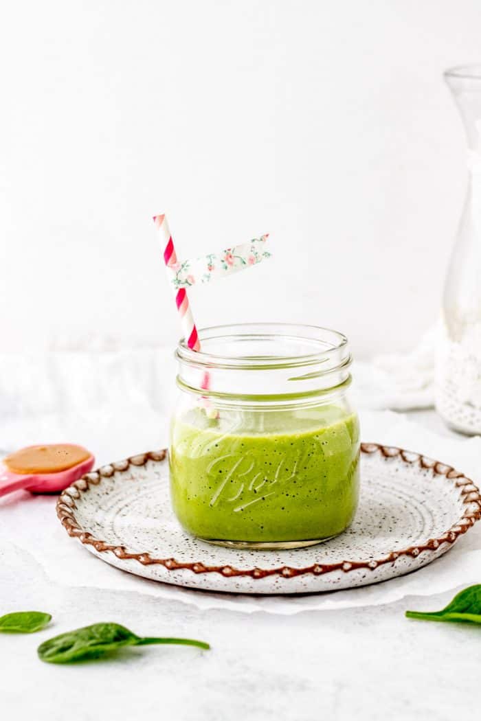 vibrant green smoothie in a jar with a straw.