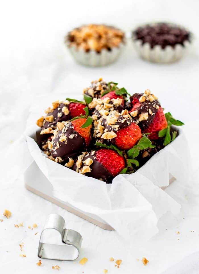 Chocolate covered strawberries with walnuts in a white box.