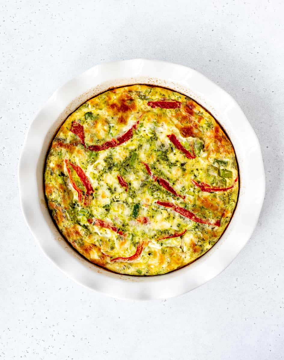 The baked crustless asparagus quiche in a white dish.