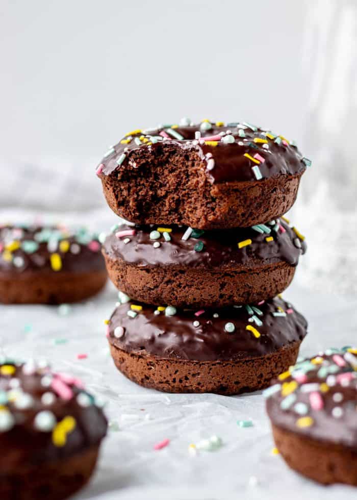 Baked chocolate donuts with sprinkles on top of each other.