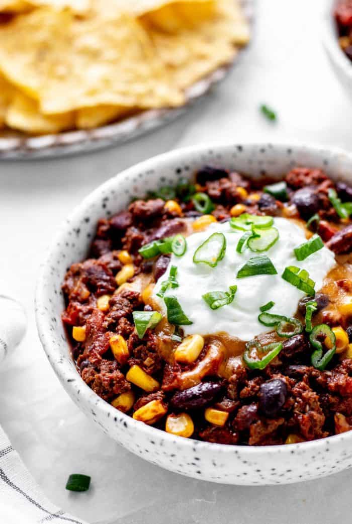 Side shot of chili in a bowl next to tortilla chips.