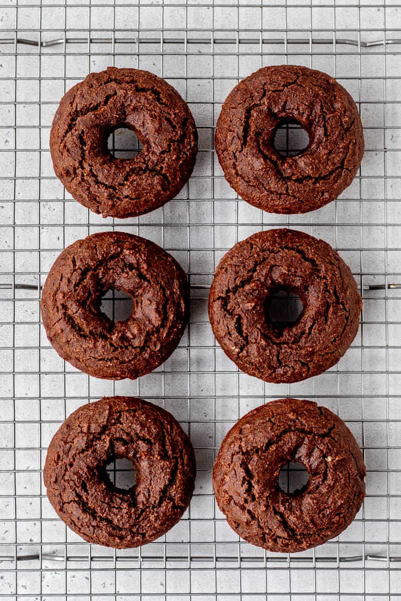Baked chocolate donuts on a cooling rack.
